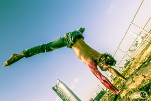 Free runner doing a handstand with bodypainted arm muscles