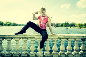 Juggling model with chest muscle bodypaint posing on bridge