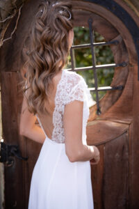 An elegant bridal hairstyle on a pretty bride in white dress.