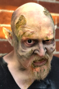 A man with behemoth Halloween makeup using prosthetics.