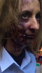 Horrific gore makeup with prosthetics on a woman's face.