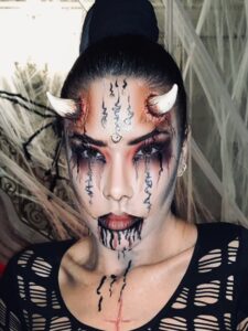 A woman with Halloween makeup and prosthetic horns.