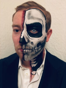 A half skull face paint on a man for Halloween.