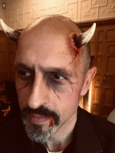 A man with prosthetic devil horns for Halloween.