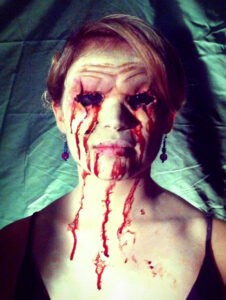 A woman with prosthetics on her face for Halloween, giving the illusion of having no eyes.