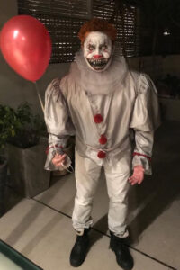 Scary clown Halloween face paint on a man holding a balloon.