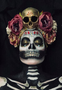 Halloween skeleton and skull makeup on a woman wearing a head dress.
