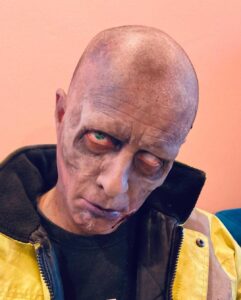 A man with zombie makeup and bald head.