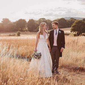 A bride and groom walking in a field.
