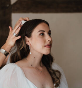 A bride has her hair styled before her wedding.