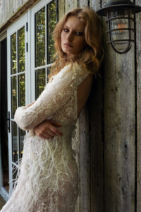 A pretty bride leaning against a rustic shed.