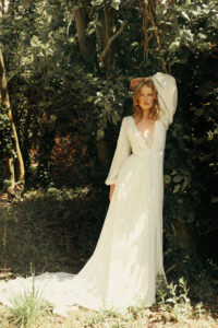 A pretty bride stands in a picturesque natural setting.