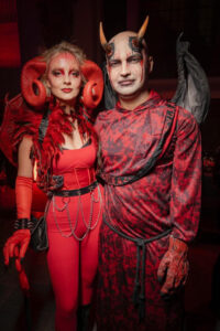 A couple in devil costumes with demon makeup.