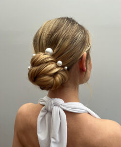 A bride's hairstyle worn up with pearl adornments.